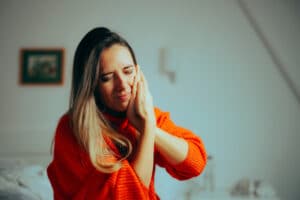 A woman holding her hands over her jaw because of TMJ pain